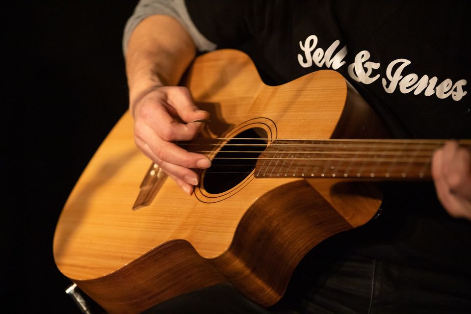 Detailaufnahme eines Gitarrenspielers mit T-Shirt und Bandaufdruck von &quot;Sell &amp; Jenes&quot; (Foto: Sell &amp; Jenes Privat)